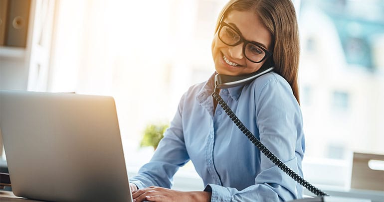 Dame arbeitet am Laptop und telefoniert