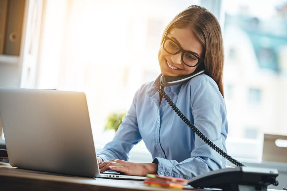 Dame arbeitet am Laptop und telefoniert