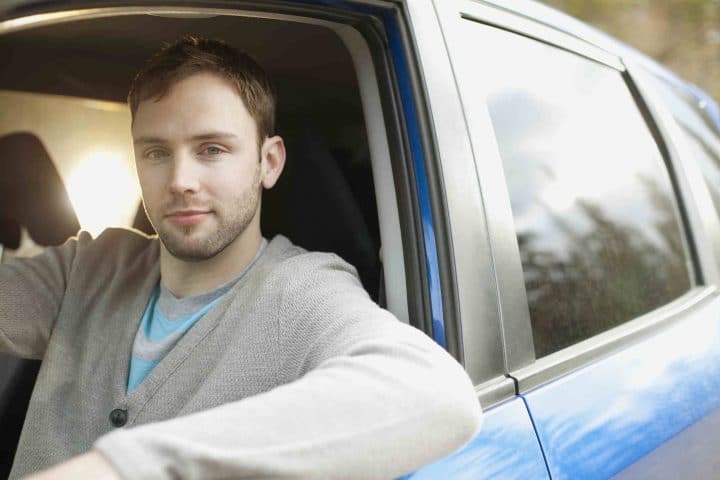 Junger Mann sitzt in einem Auto.