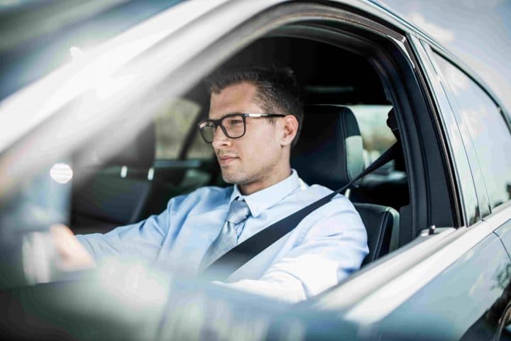 Mann sitzt am Steuer eines Firmenautos.