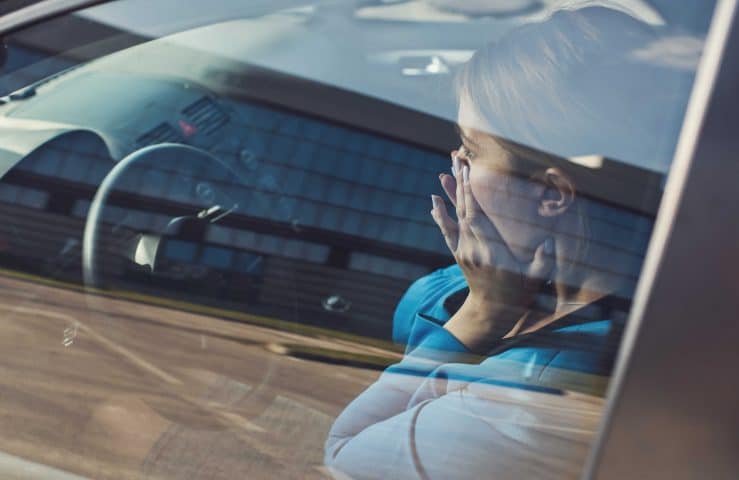 Frau sitzt mit Angst beim Autofahren hinter dem Steuer.