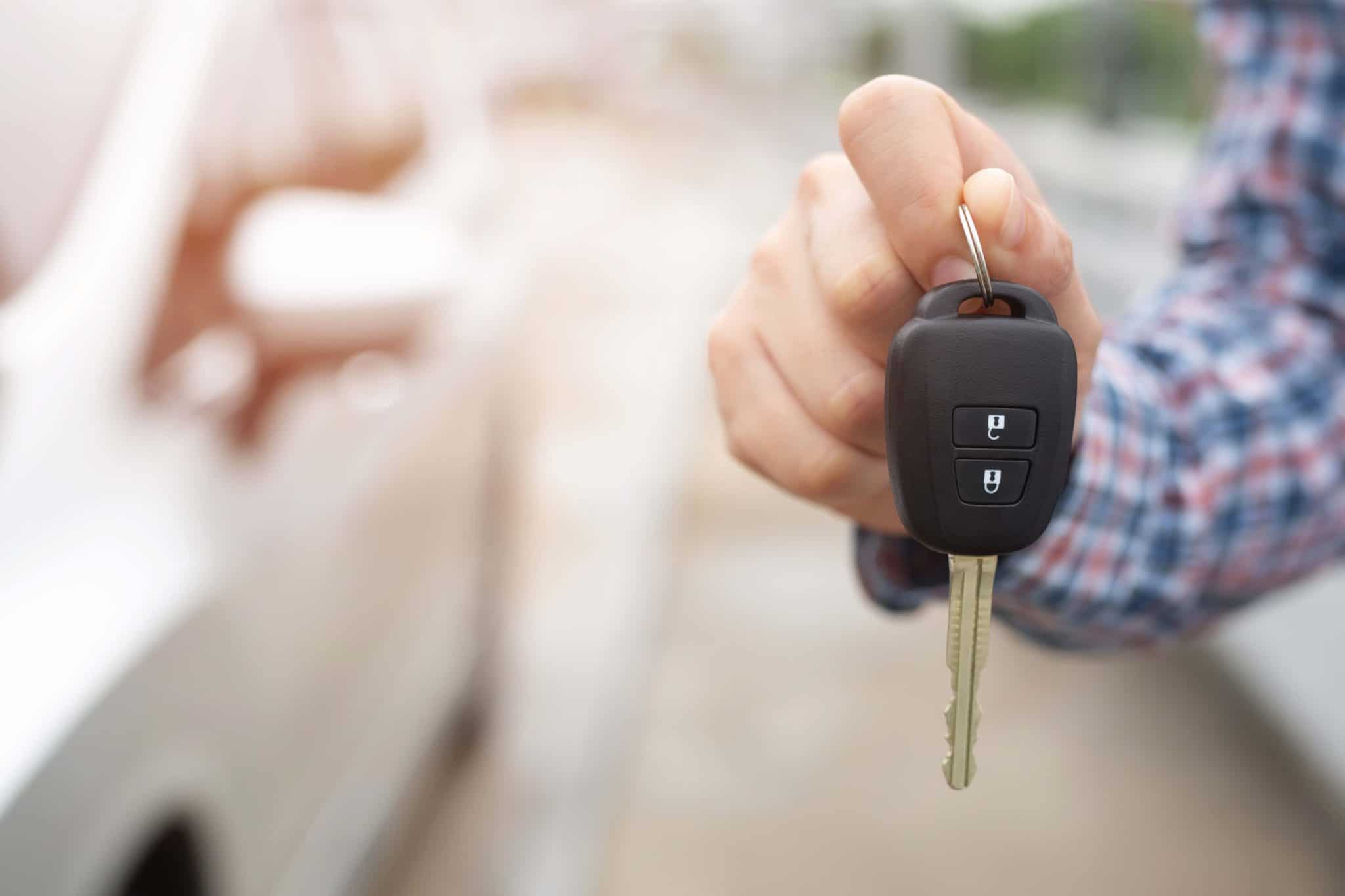 Ein Mann hält seine Autoschlüssel vor einem Auto