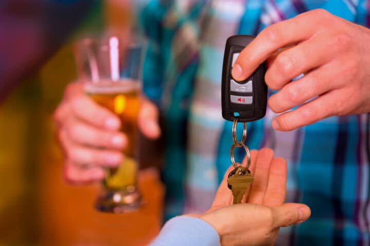 Person nimmt Bier trinkendem Mann den Autoschlüssel ab